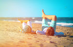 Symbolbild durch ein Foto, Vater und Sohn liegen in gleicher Pose auf dem Rücken am Strand Symbolbild durch ein Foto, Vater und Sohn liegen in gleicher Pose auf dem Rücken am Strand