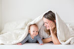 Symbolbild in Form eines Babys und einer Mutter, die neben einander liegen und darüber ist eine weiße Decke gebreitet. 