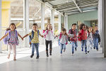 Kinder, die sich an den Händen halten und mit Schultaschen durch einen Ganz laufen Kinder, die sich an den Händen halten und mit Schultaschen durch einen Ganz laufen