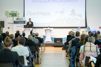Moderator Oliver Zeisberger am Podium, Fotoaufnahme von hinten in die vollen Ränge Moderator Oliver Zeisberger am Podium, Fotoaufnahme von hinten in die vollen Ränge
