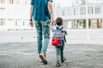 Ein Vater spaziert mit seinem Kind an der Hand.
