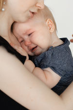 Ein Baby weint am Arm seiner Mutter. Ein Baby weint am Arm seiner Mutter.