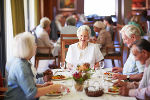 Symbolbild mit älteren Menschen, die an einem Tisch sitzen und essen. 